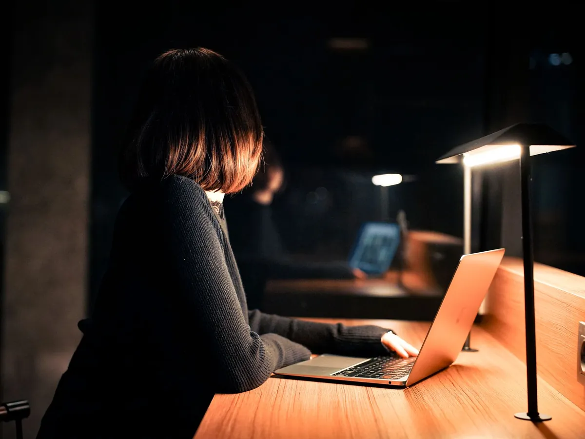 Femme travaillant sur son ordinateur portable sous une lumière chaleureuse, ambiance nocturne calme