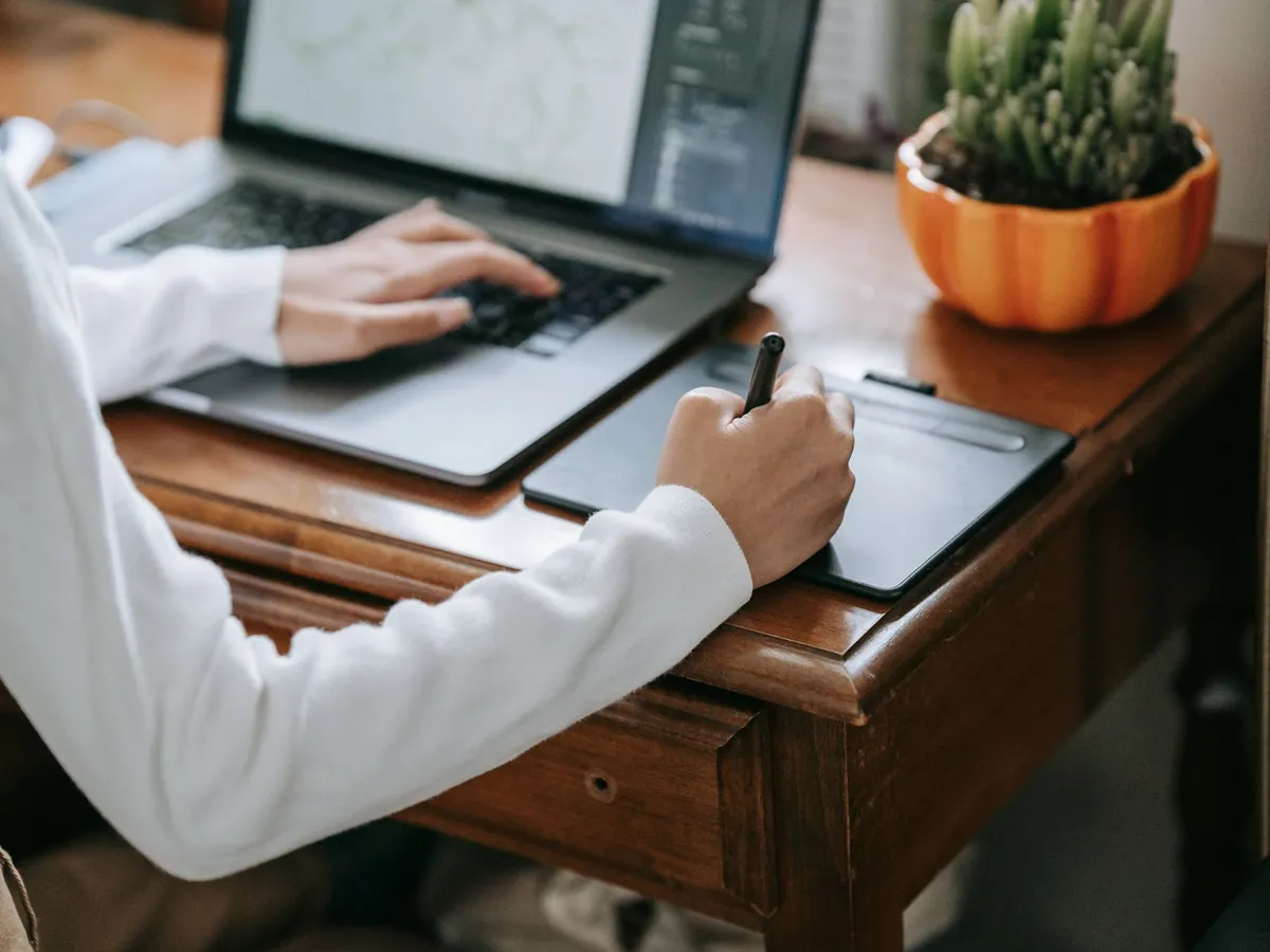 Gros plan d'un designer sur une tablette graphique et un ordinateur portable, travail créatif numérique
