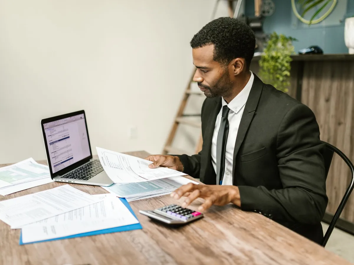 Homme d'affaires en costume travaillant sur des documents et un ordinateur portable à son bureau