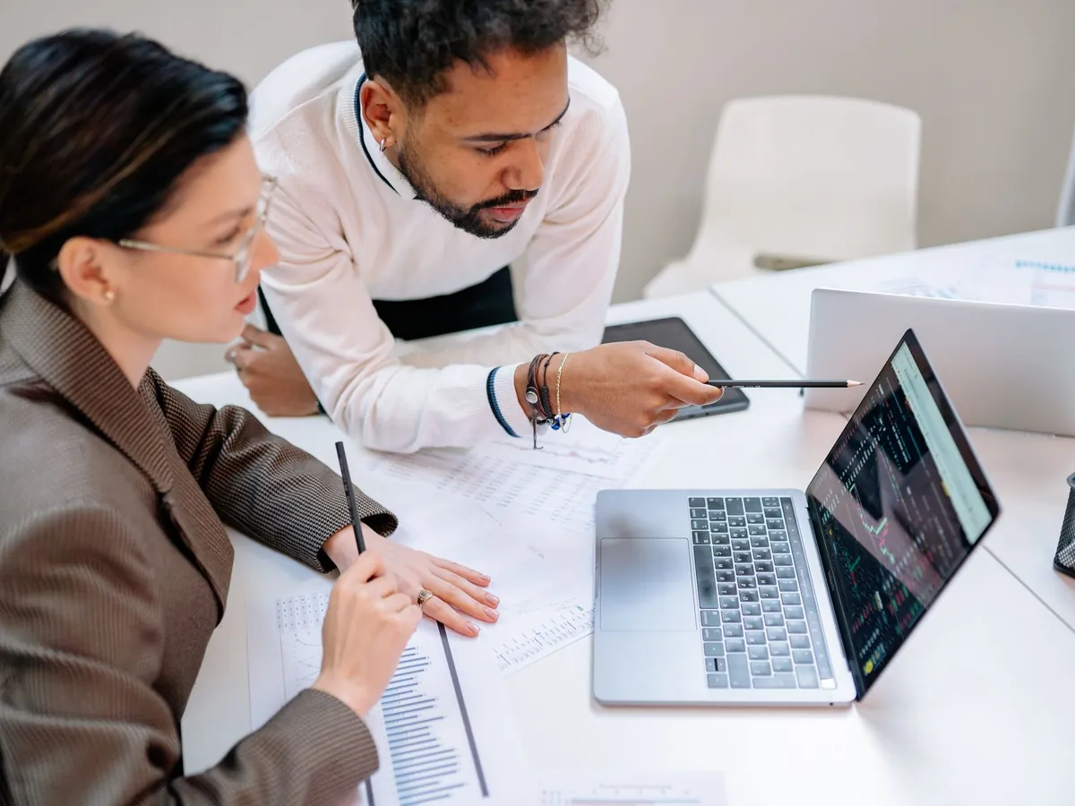 Professionnels d'affaires discutant de données à un bureau avec un ordinateur portable