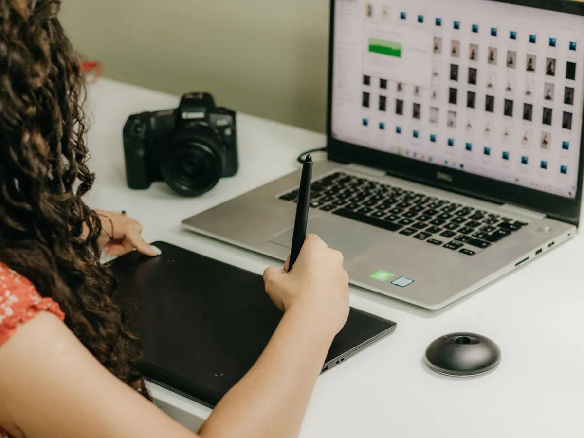 Femme utilisant une tablette graphique et un ordinateur portable pour relire ses photos