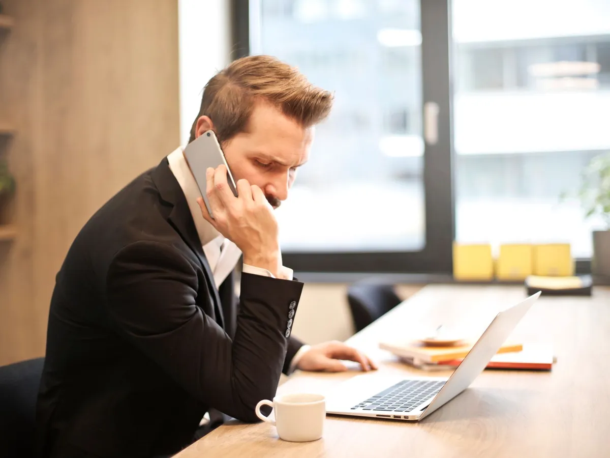 Homme d'affaires en costume, au téléphone, travaillant sur son ordinateur portable