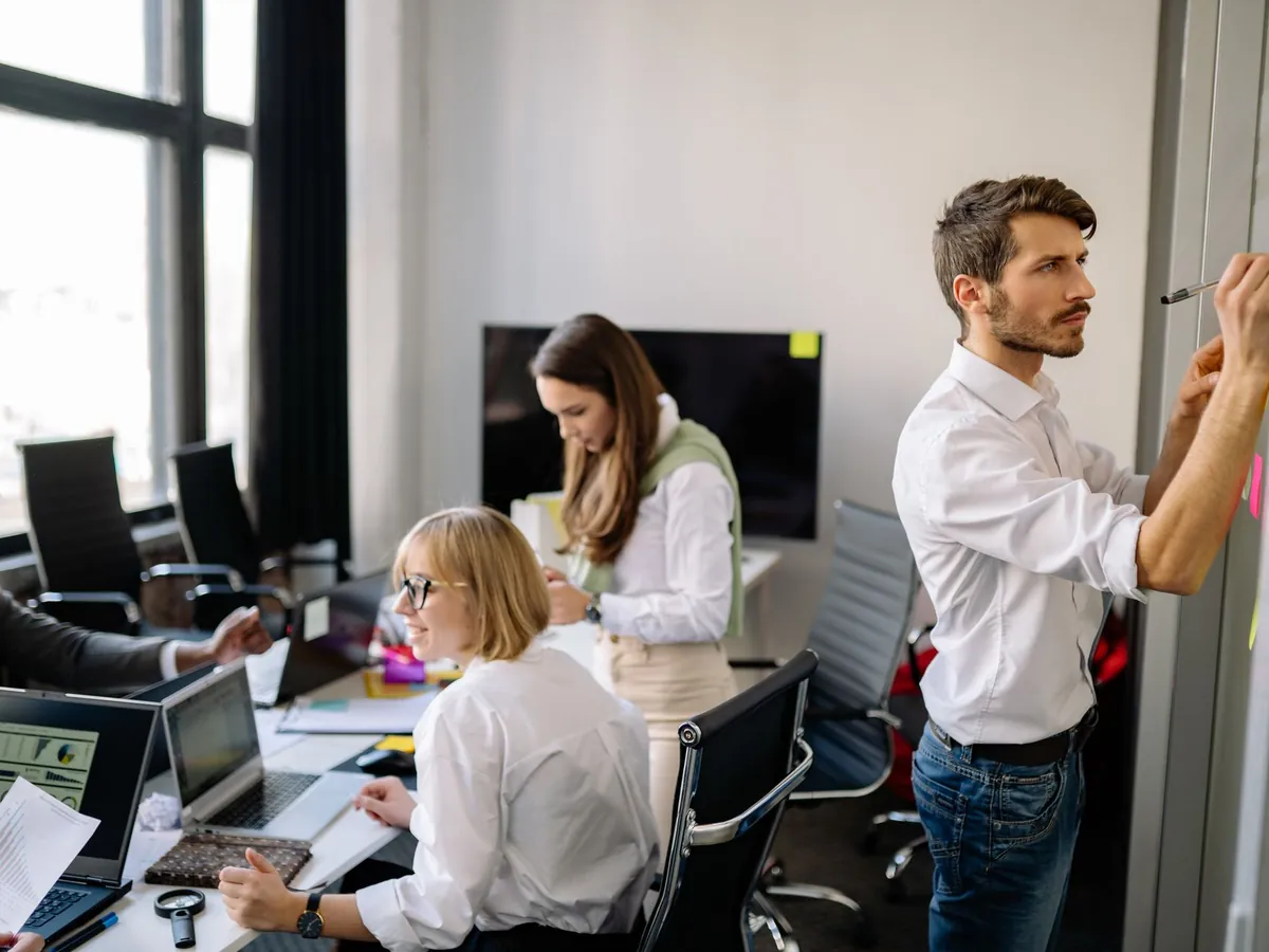 Groupe diversifié de collègues collaborant dans un bureau moderne, partageant idées et planification