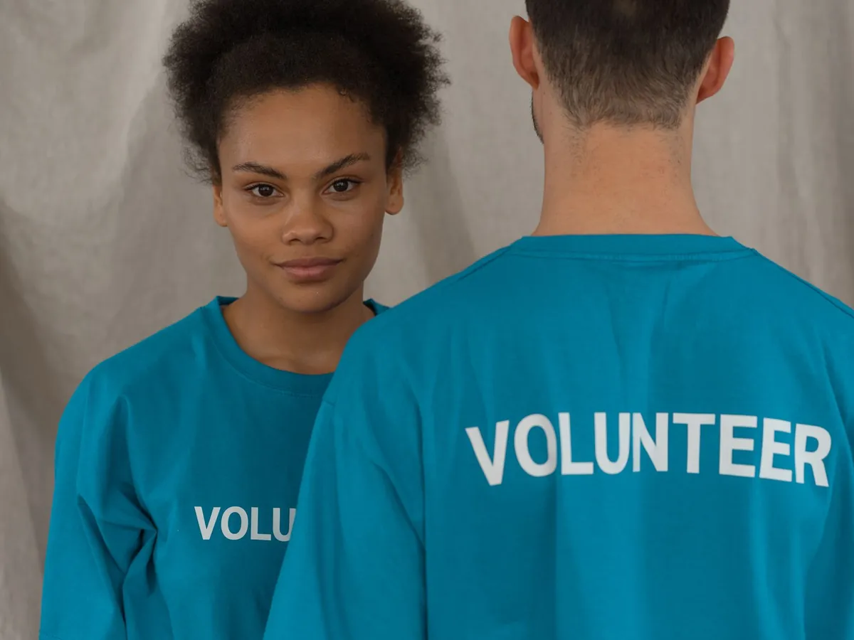 Deux bénévoles en chemise bleue, dont une souriante face à la caméra