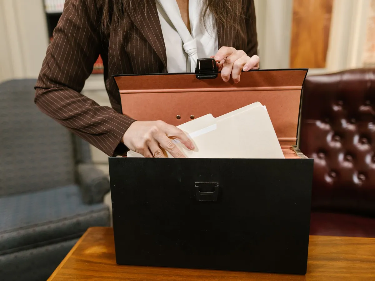Gros plan d'une femme d'affaires classant des dossiers dans une boîte noire, au bureau