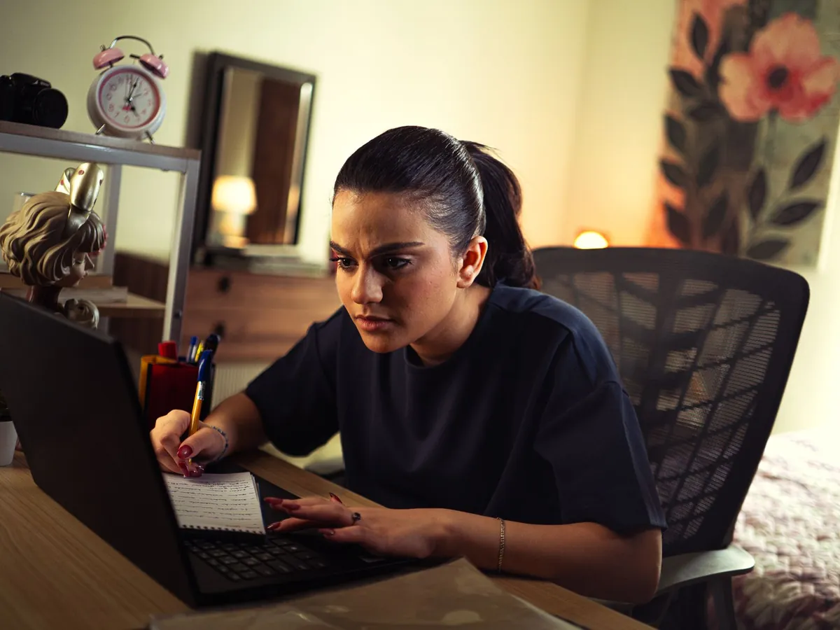 Jeune femme étudiant intensément sur son ordinateur portable, à un bureau bien éclairé