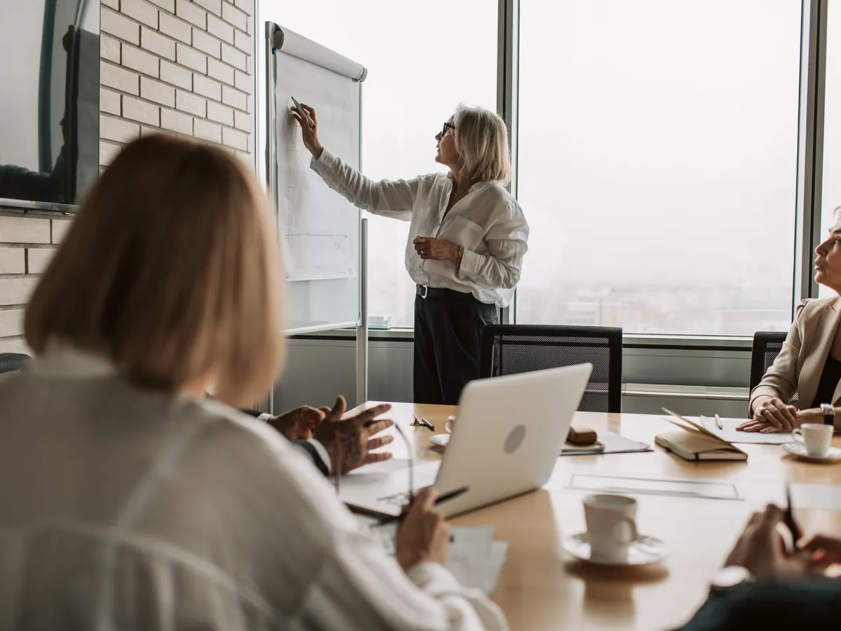 Dirigeant présentant une stratégie sur tableau blanc lors d'une réunion au bureau