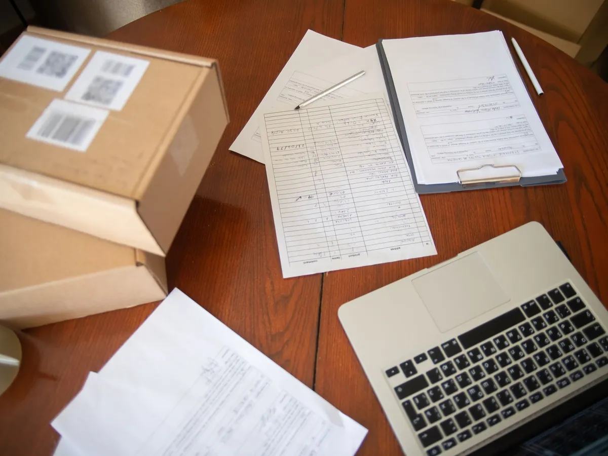 Vue à plat d'un espace de travail : ordinateur portable, documents et cartons d'expédition