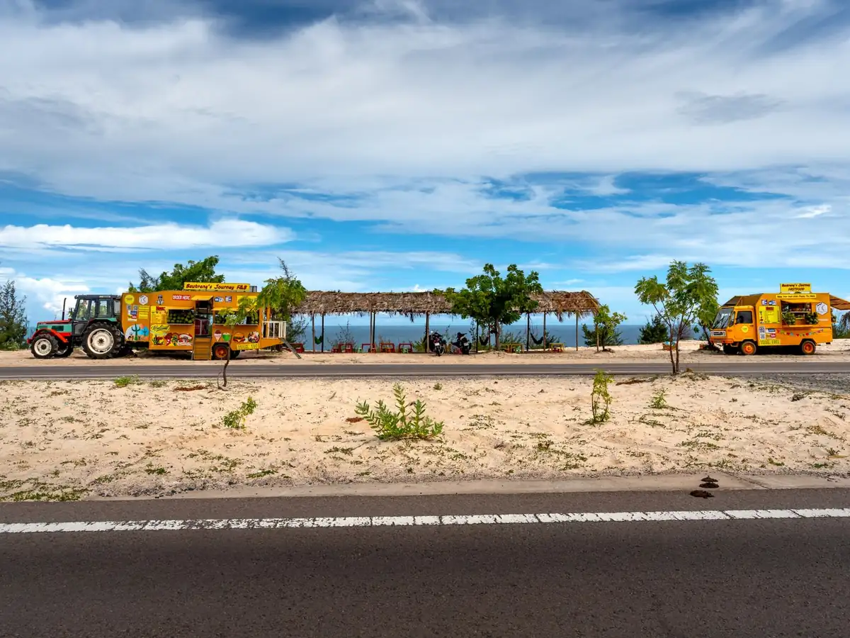 Food trucks colorés garés près d'une plage tropicale, sous un ciel éclatant