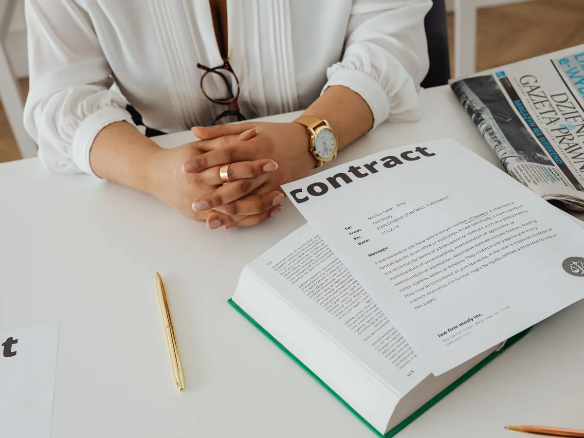 Femme d'affaires assise à son bureau, relisant un contrat, avec documents juridiques et journal