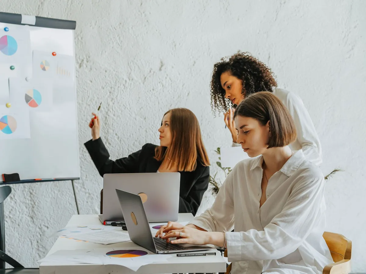 Femmes travaillant ensemble sur un projet avec ordinateurs portables et graphiques, équipe diversifiée