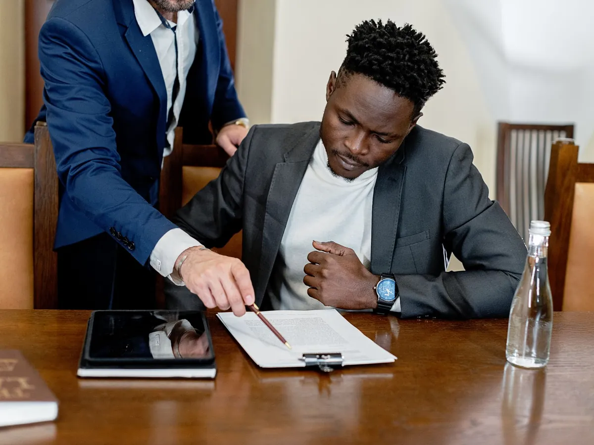 Deux hommes d'affaires en consultation juridique examinant un document sur une tablette posée au bureau