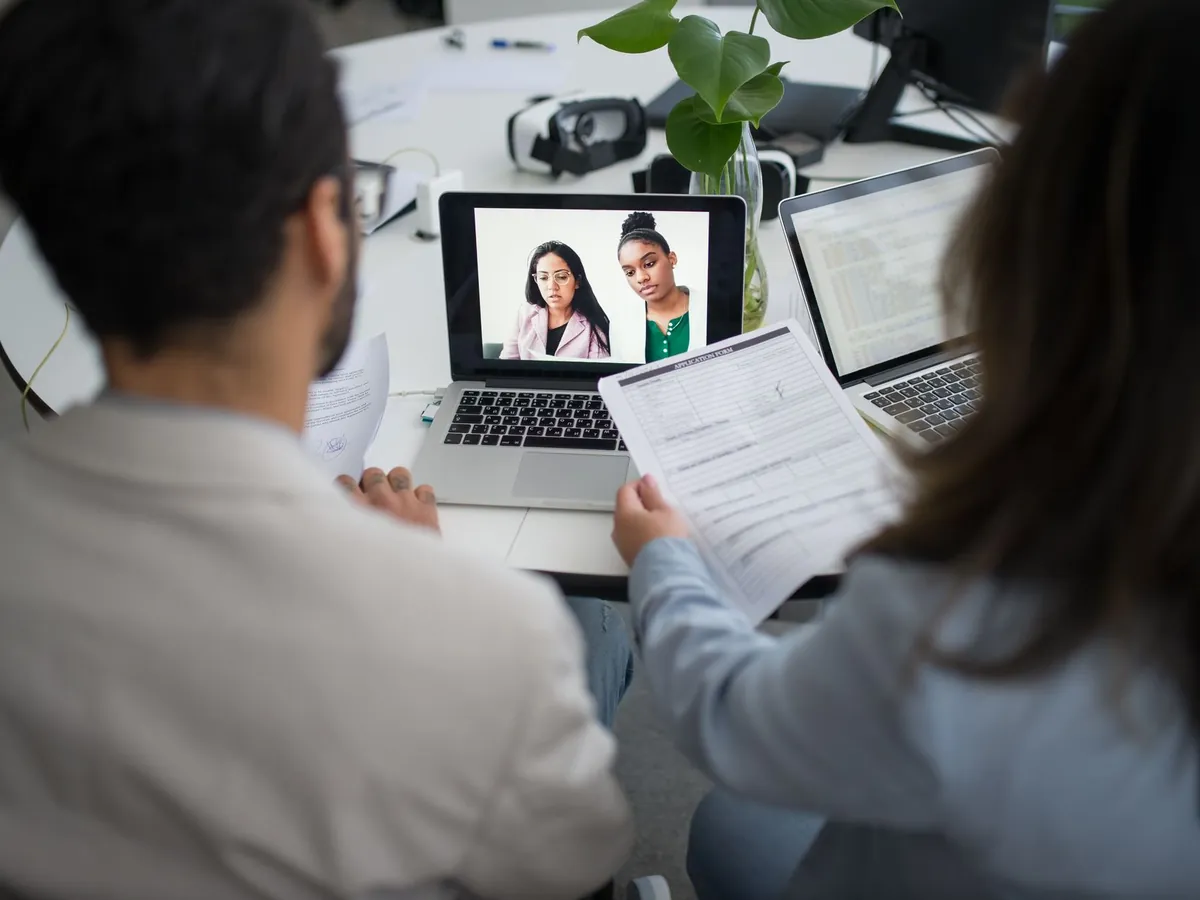Deux professionnels en entretien d'embauche par visioconférence, ordinateurs portables ouverts