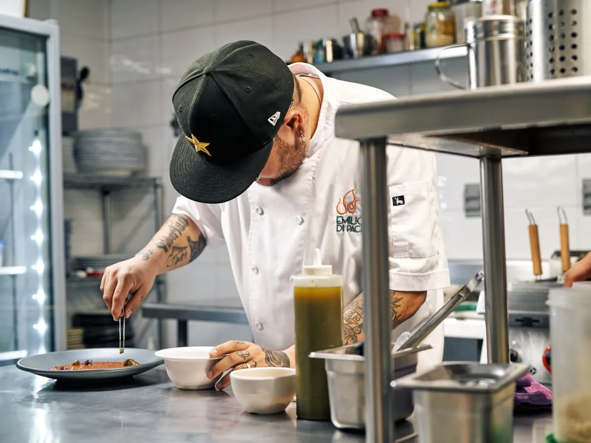 Chef dressant soigneusement une assiette avec précision et art, en cuisine professionnelle