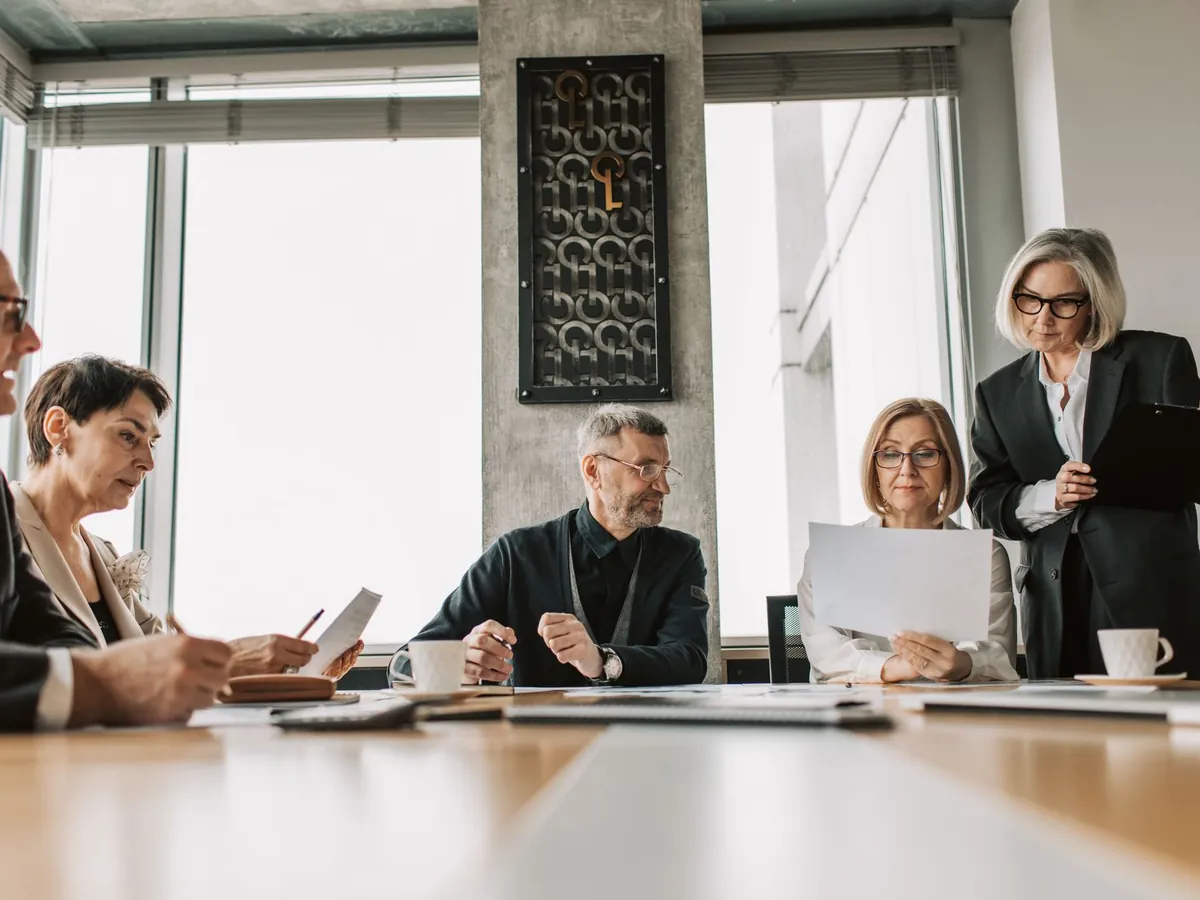 Professionnels d'entreprise échangeant sur des documents dans une salle de réunion moderne