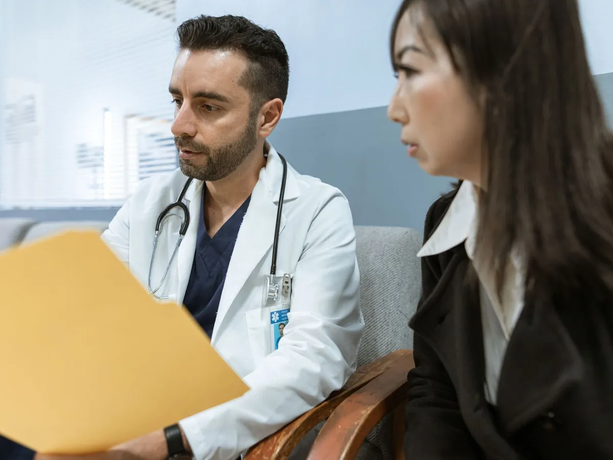 Médecin discutant de dossiers médicaux avec un patient dans un cadre clinique