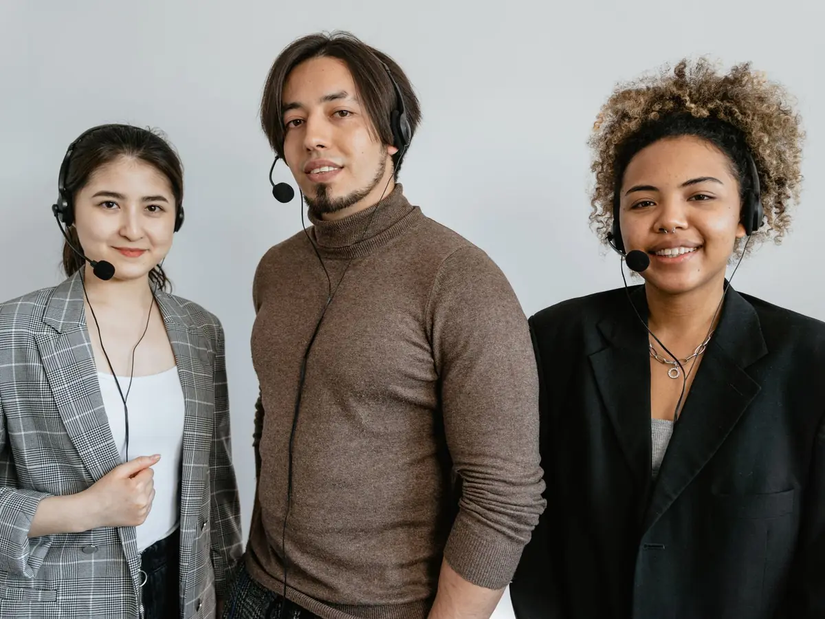 Trois employés de centre d'appels diversifiés, casque sur la tête, prêts à aider les clients