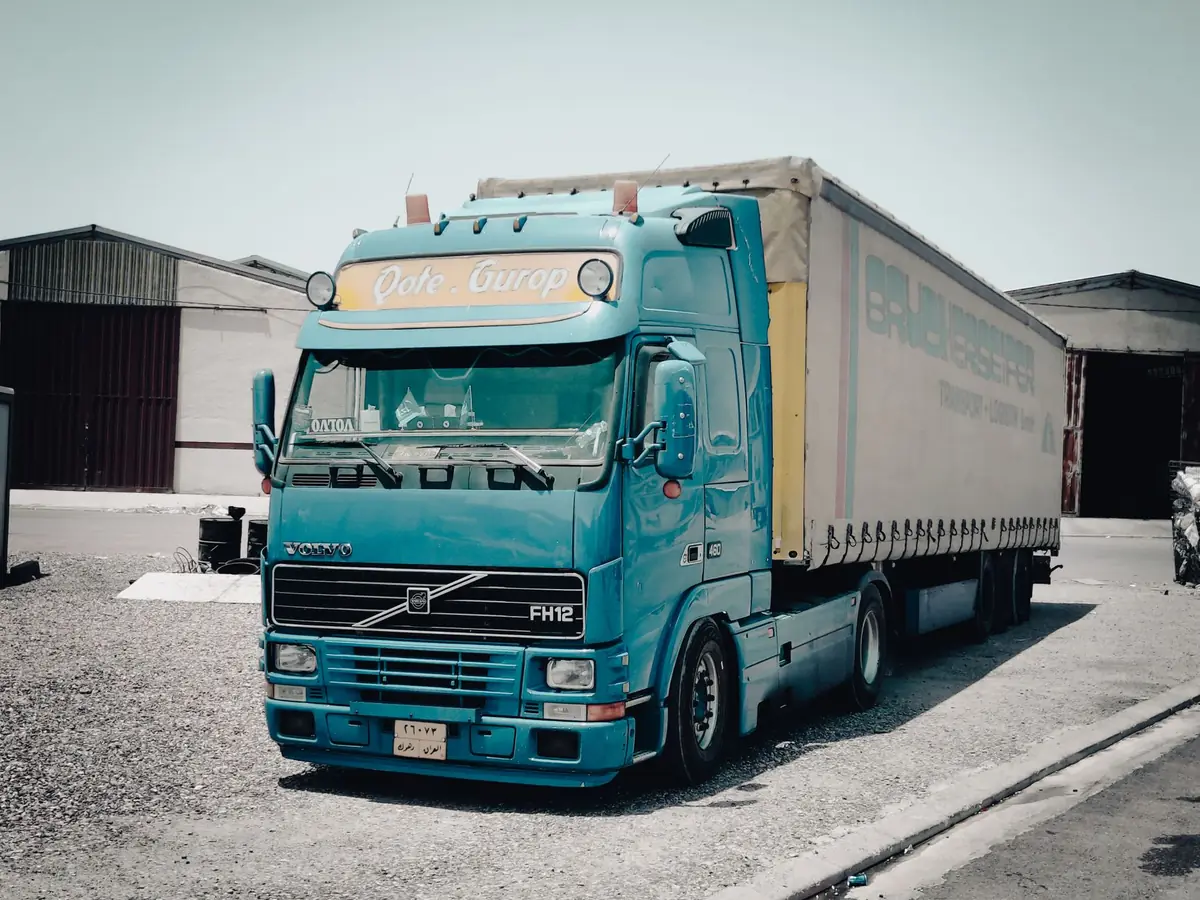 Camion Volvo bleu garé devant un entrepôt dans une zone industrielle, scène de jour