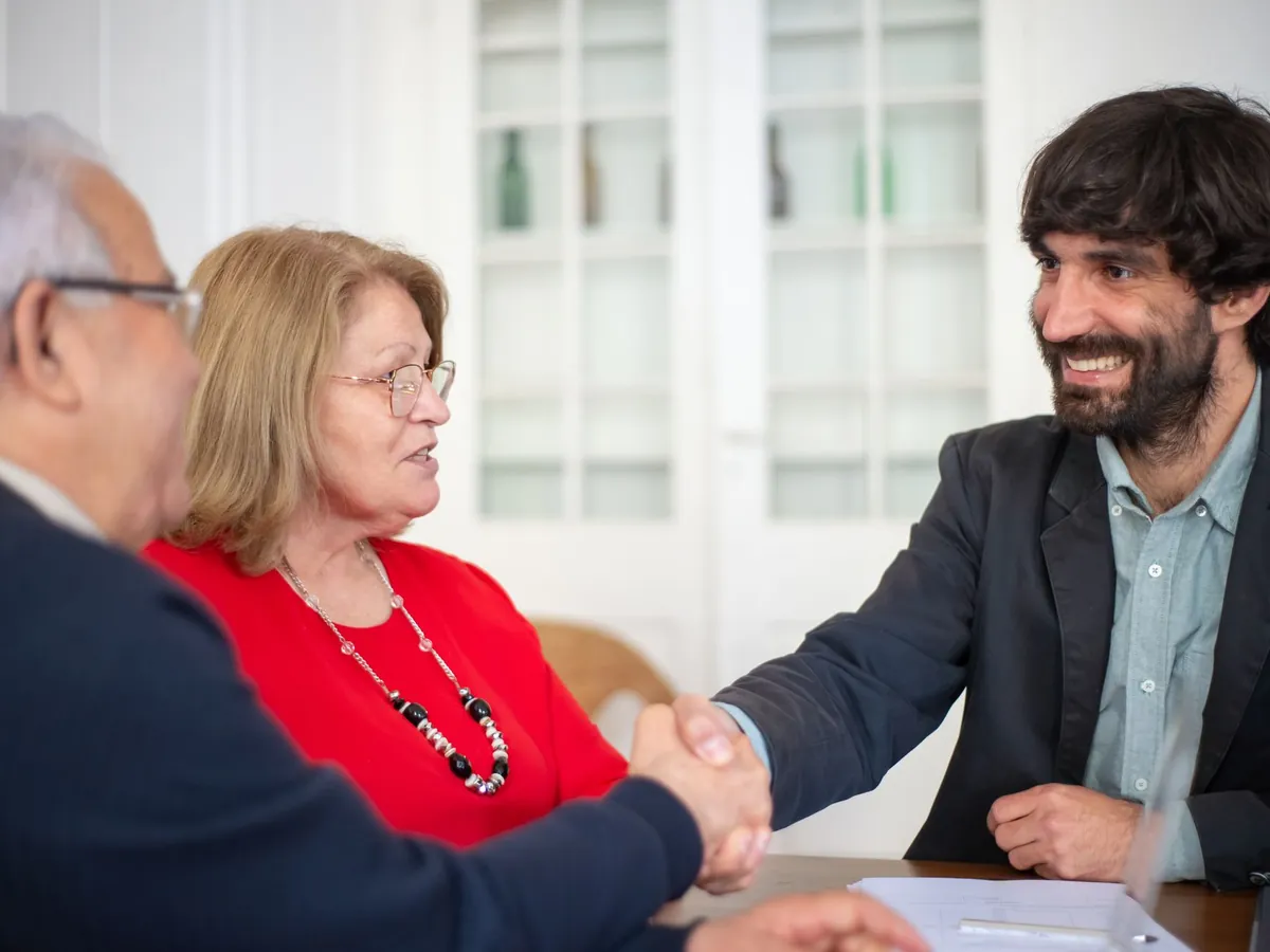 Conseiller en assurance serrant la main d'un couple de clients lors d'un rendez-vous