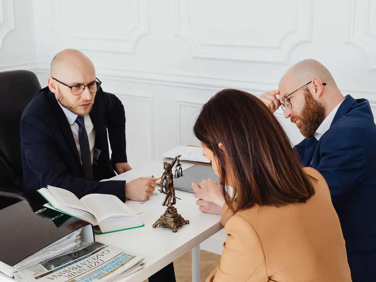Deux avocats et une cliente autour d'un dossier sur un bureau