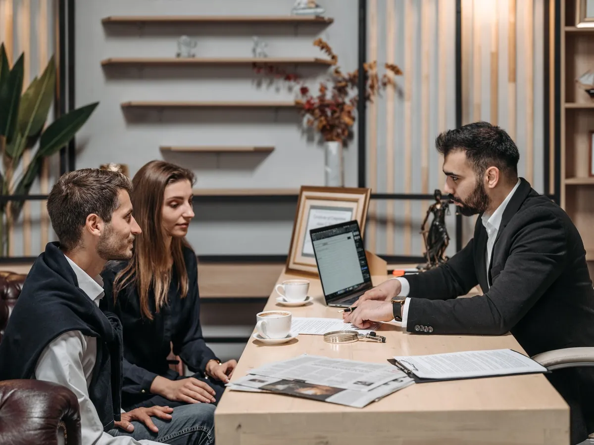 Conseiller bancaire recevant un couple devant un ordinateur portable