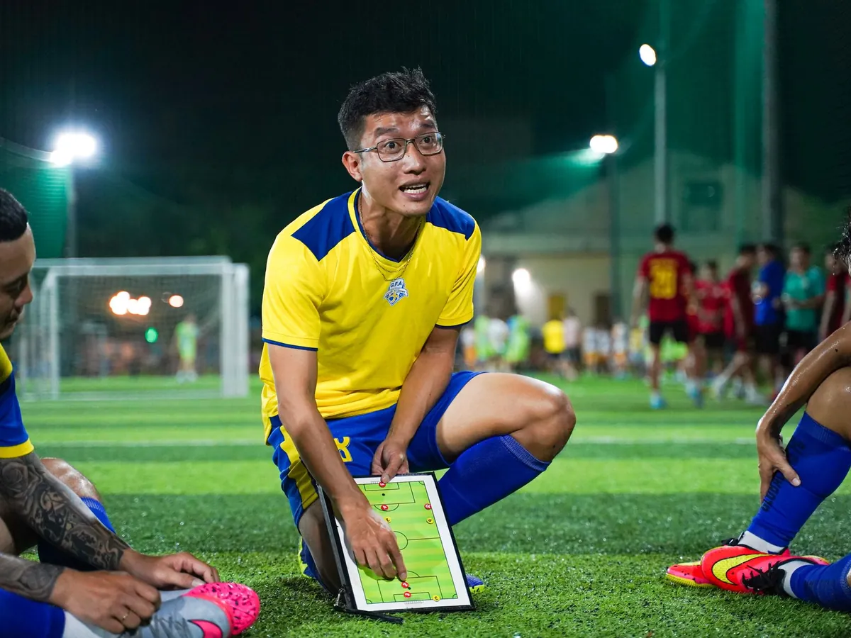 Entraîneur expliquant une tactique sur une tablette à ses joueurs sur un terrain de football