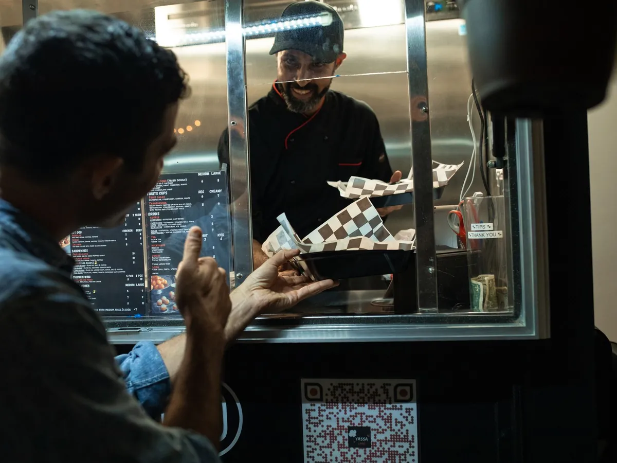 Cuisinier remettant une commande à un client à la fenêtre d'un food truck