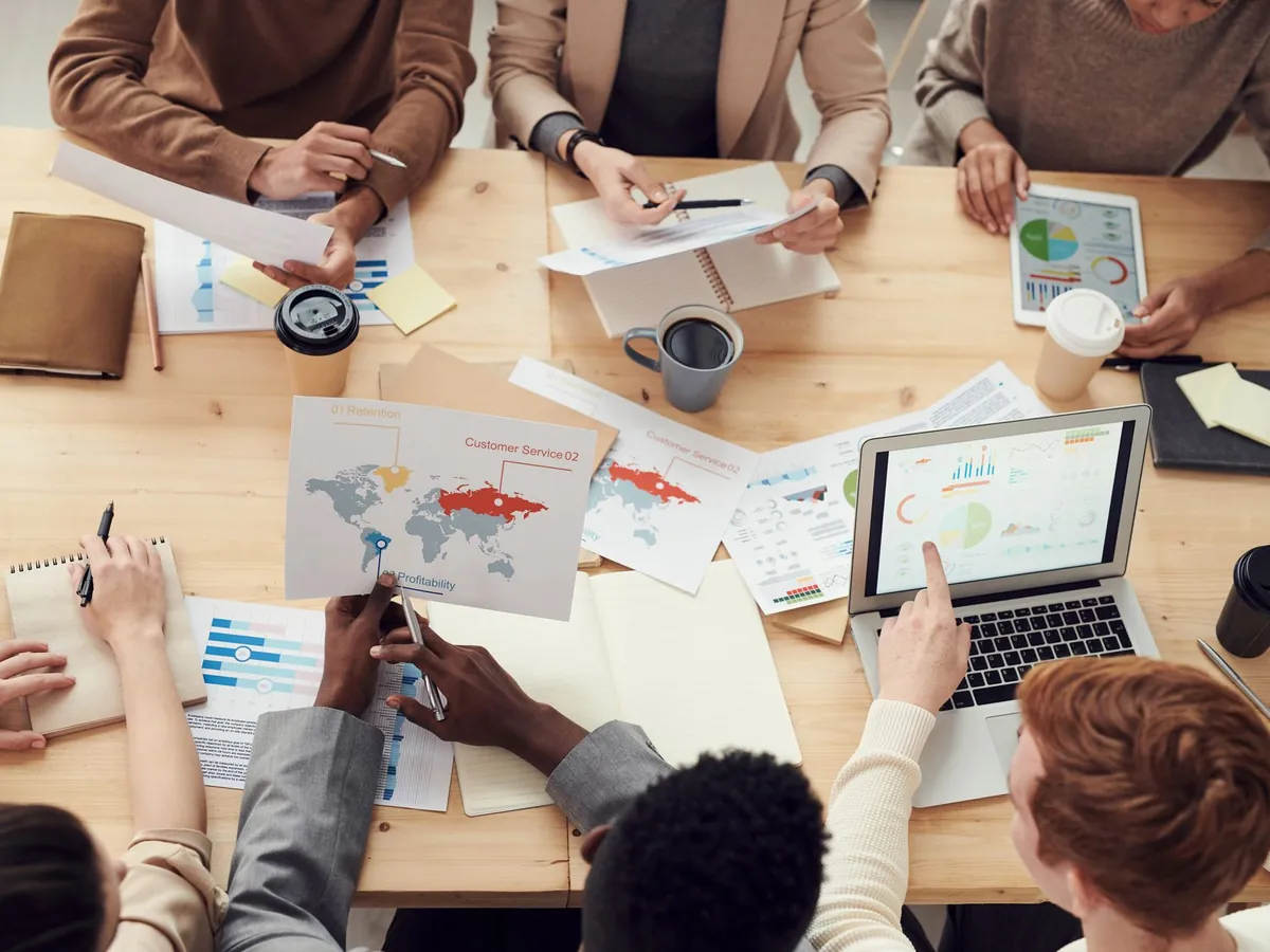 Équipe marketing réunie autour d'une table avec des graphiques et un ordinateur
