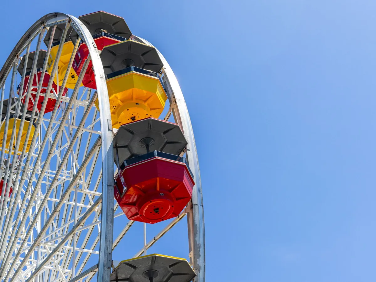 Grande roue colorée dans un parc d'attractions sous un ciel bleu
