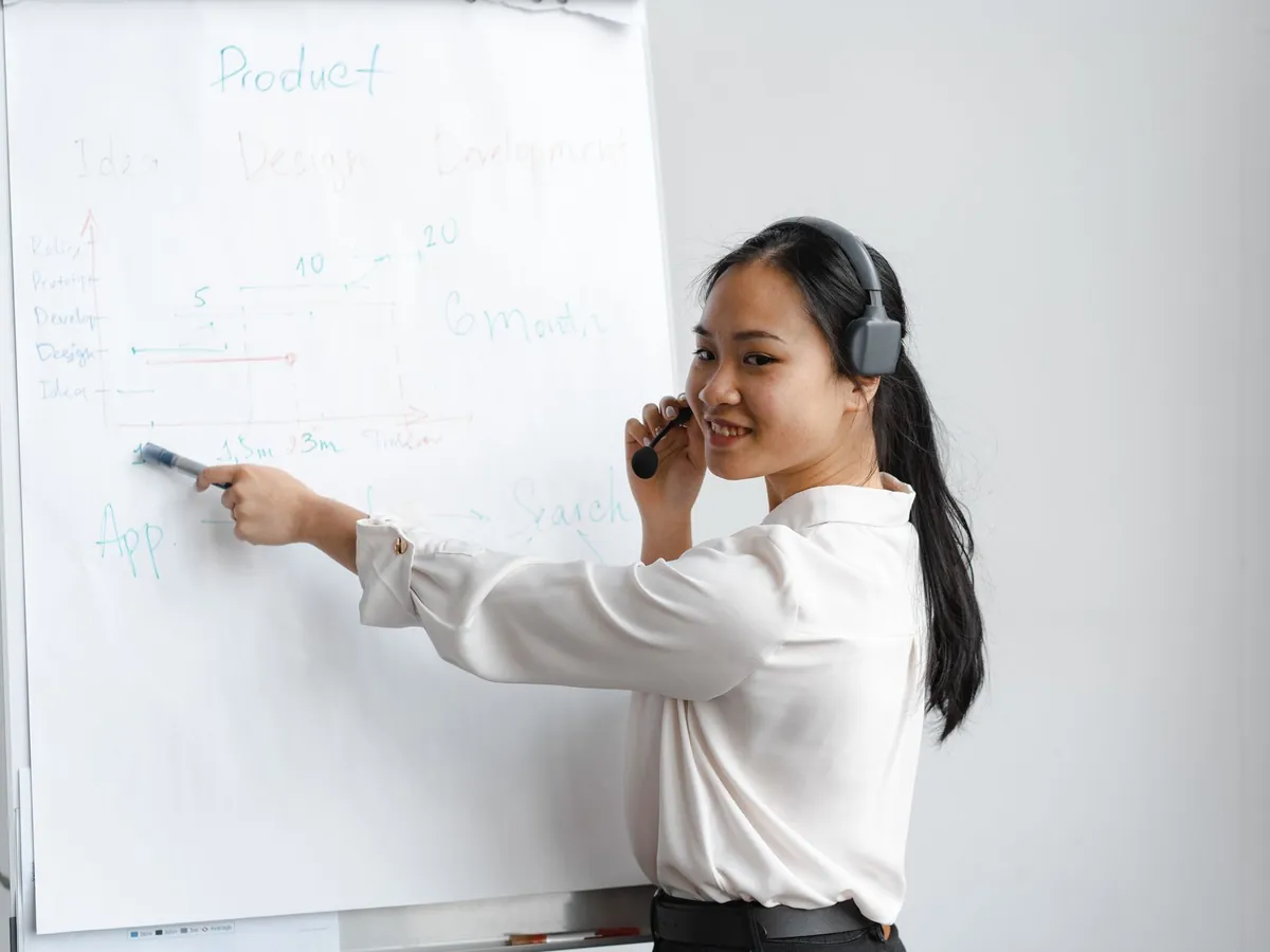 Femme asiatique au casque présentant une stratégie produit sur un tableau à feuilles mobiles, au bureau