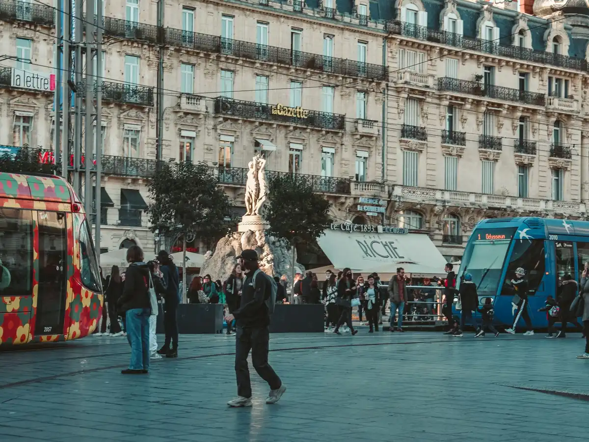 Vue animée d'une rue de Montpellier avec des tramways colorés et une architecture classique
