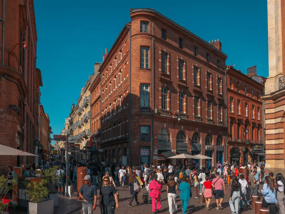 Rue animée du centre historique de Toulouse, architecture en briques rouges et passants