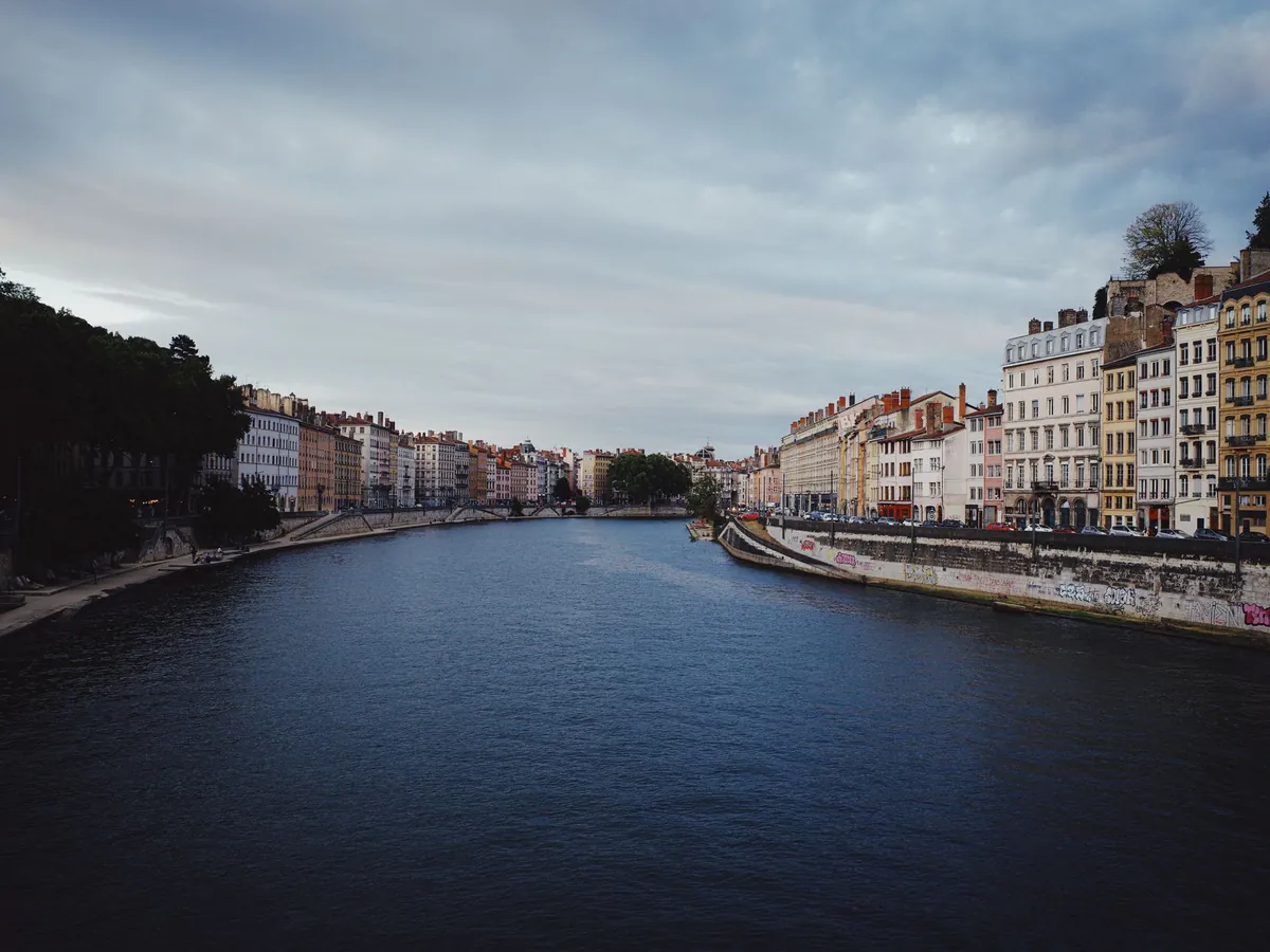 Façades au bord du fleuve à Lyon, sous un ciel dramatique