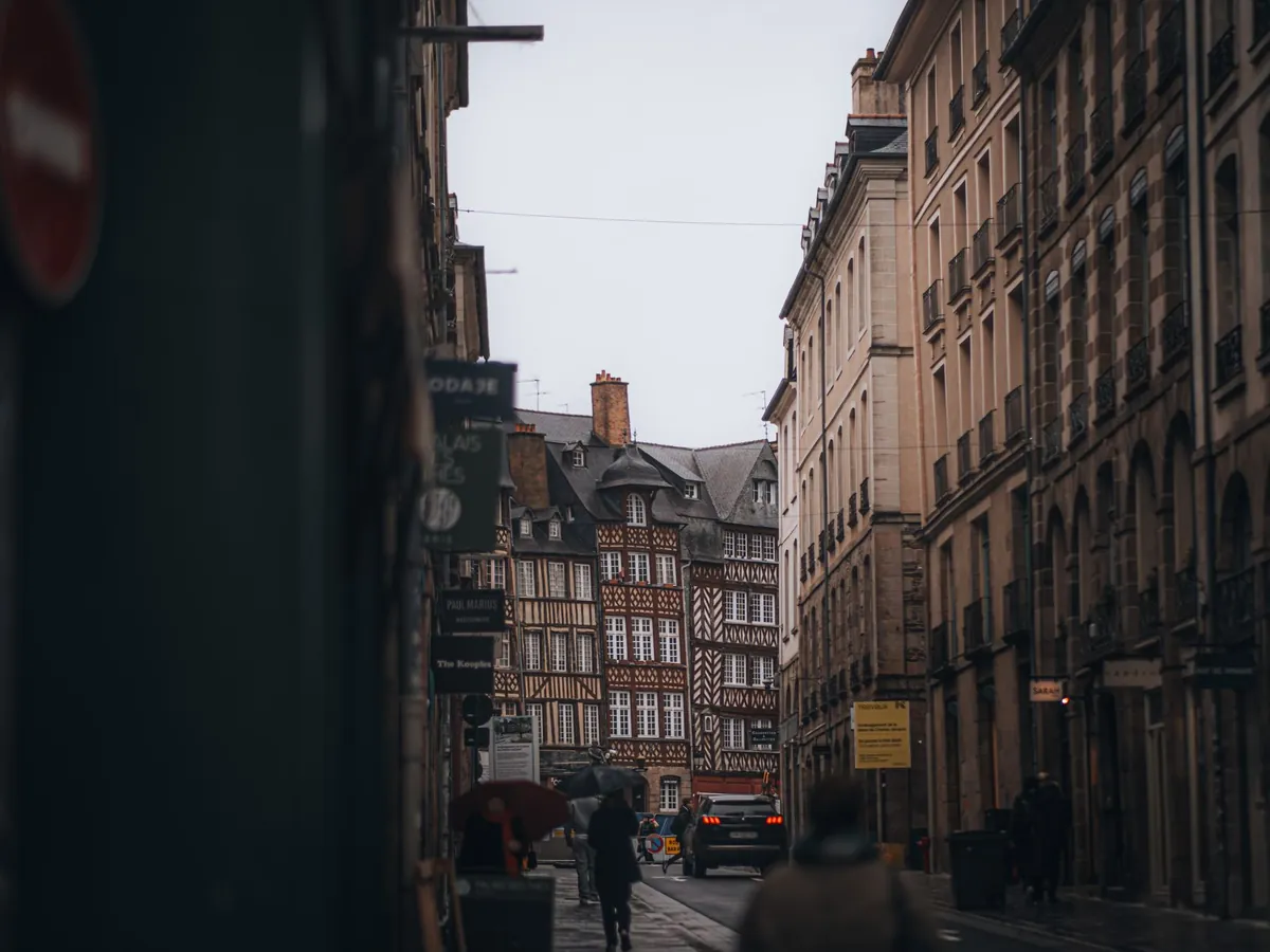 Rue pittoresque de Rennes, avec ses maisons à colombages, sous un ciel nuageux