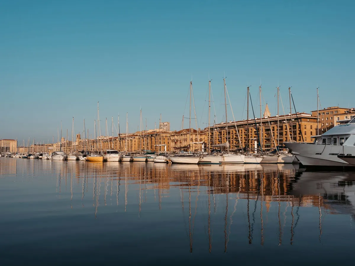 Port paisible avec des bateaux à l'ancre et des voiliers se reflétant sur des eaux calmes