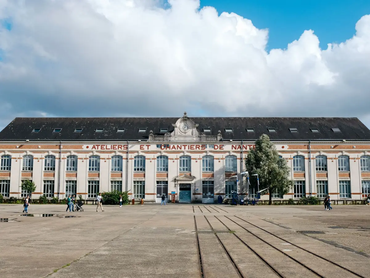 Façade des Ateliers et Chantiers de Nantes sous un ciel nuageux