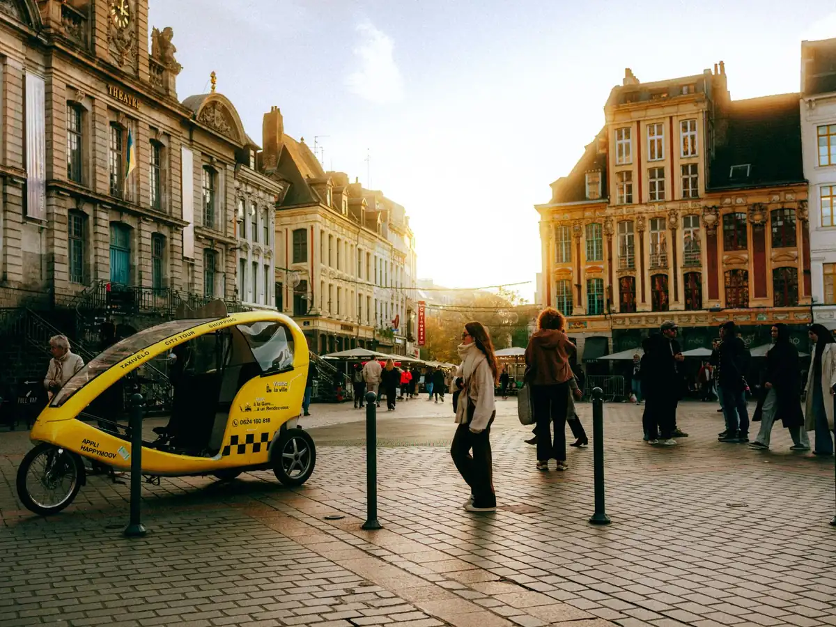 Coucher de soleil sur une place de ville animée, bâtiments historiques et pousse-pousse jaune