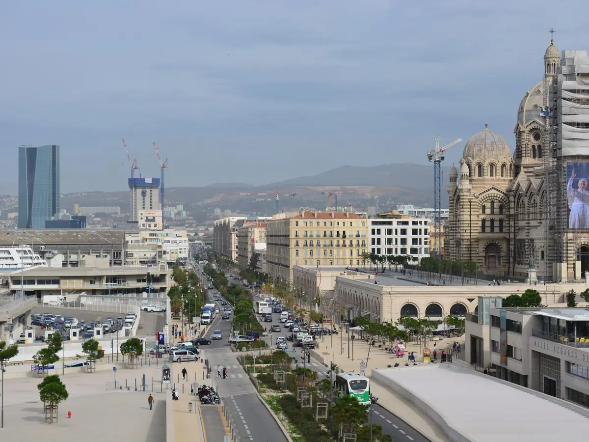 Scène urbaine animée à Marseille, avec sa cathédrale emblématique et des rues très fréquentées
